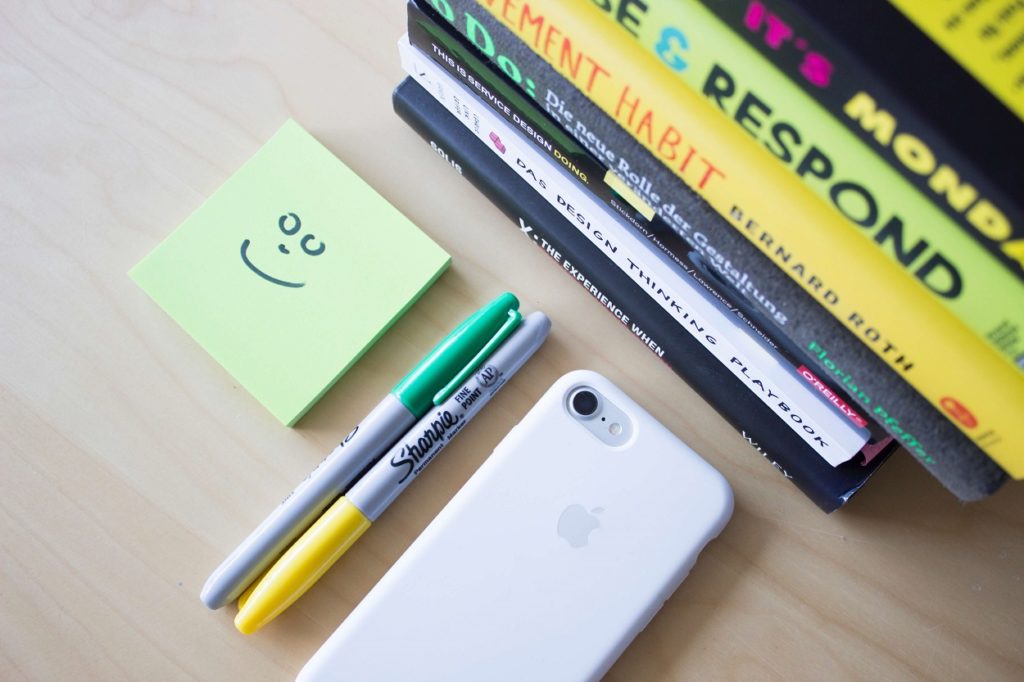 Sharpies, pens, IPhone, sticky notes and books on a desk - Healthy Habits - Laura Blog