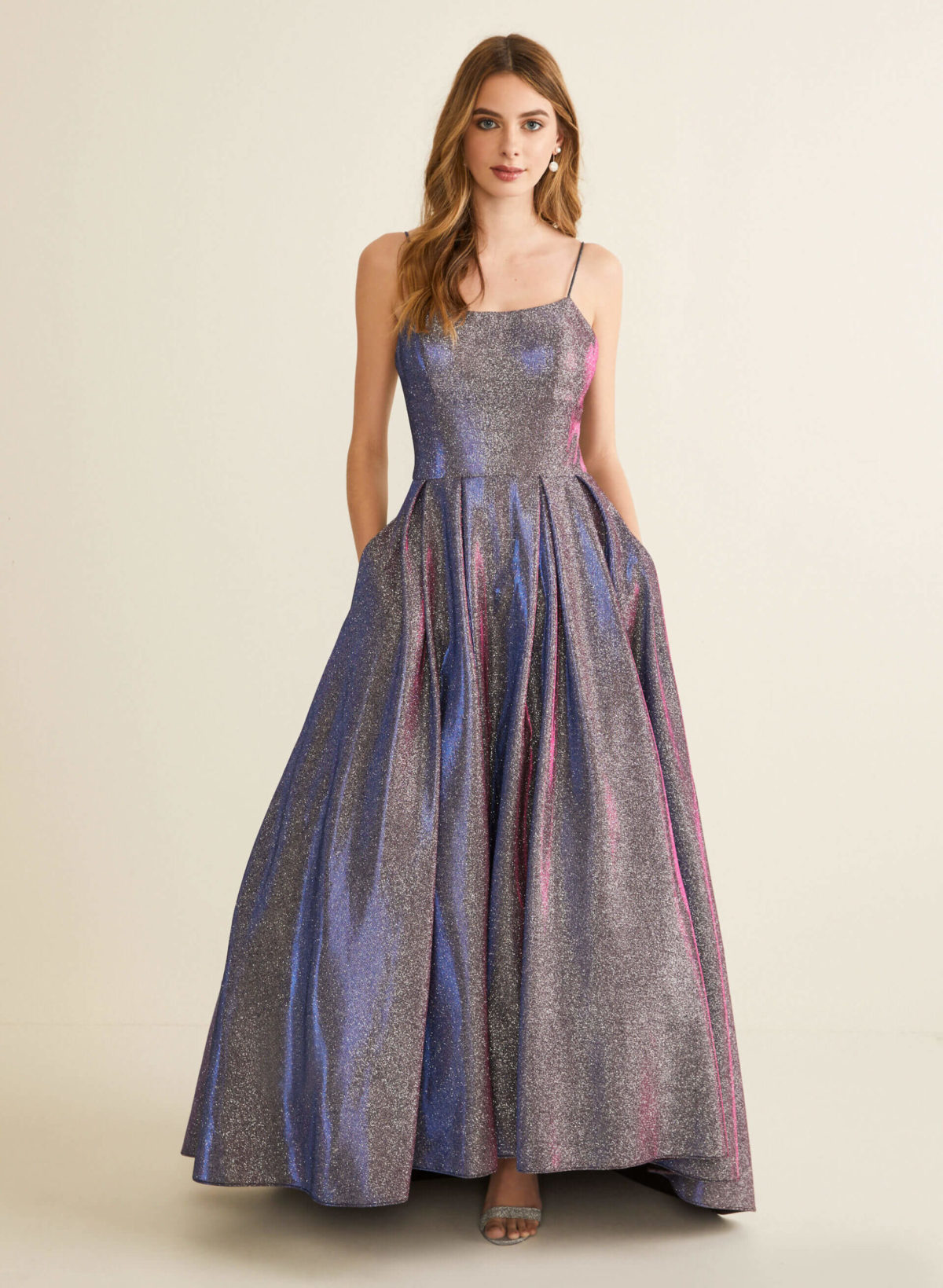 A young woman wearing a glittery metallic ball gown prom dress.