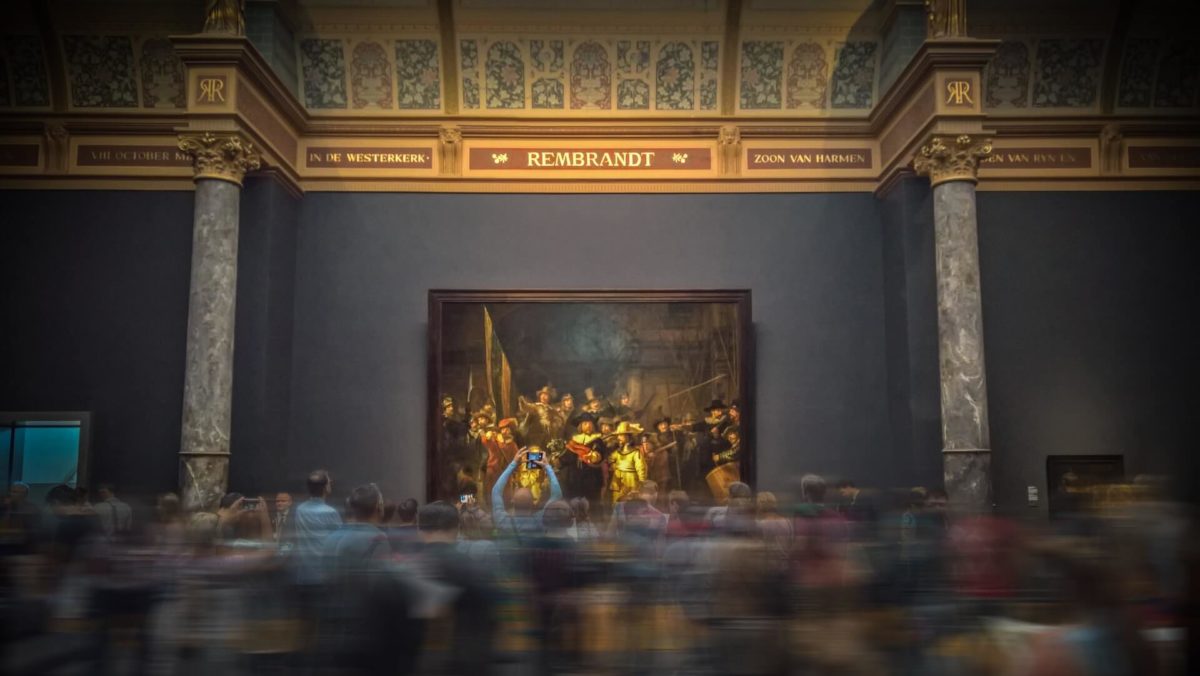 A crowd of people viewing Rembrandt's painting Night Watch at the Rijksmuseum in Amsterdam.