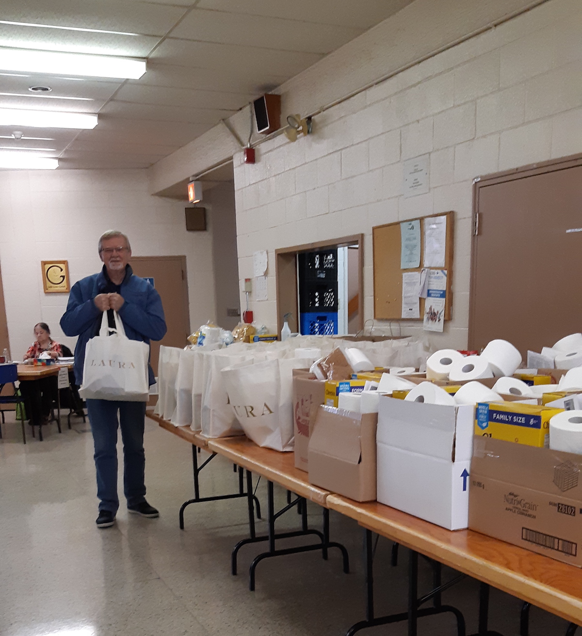 A man with a collection of donated food and reusable shopping bags at a food bank.