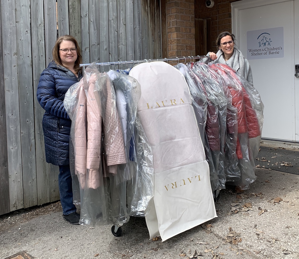 Two women with a rack of donated Laura coats at a community organization.