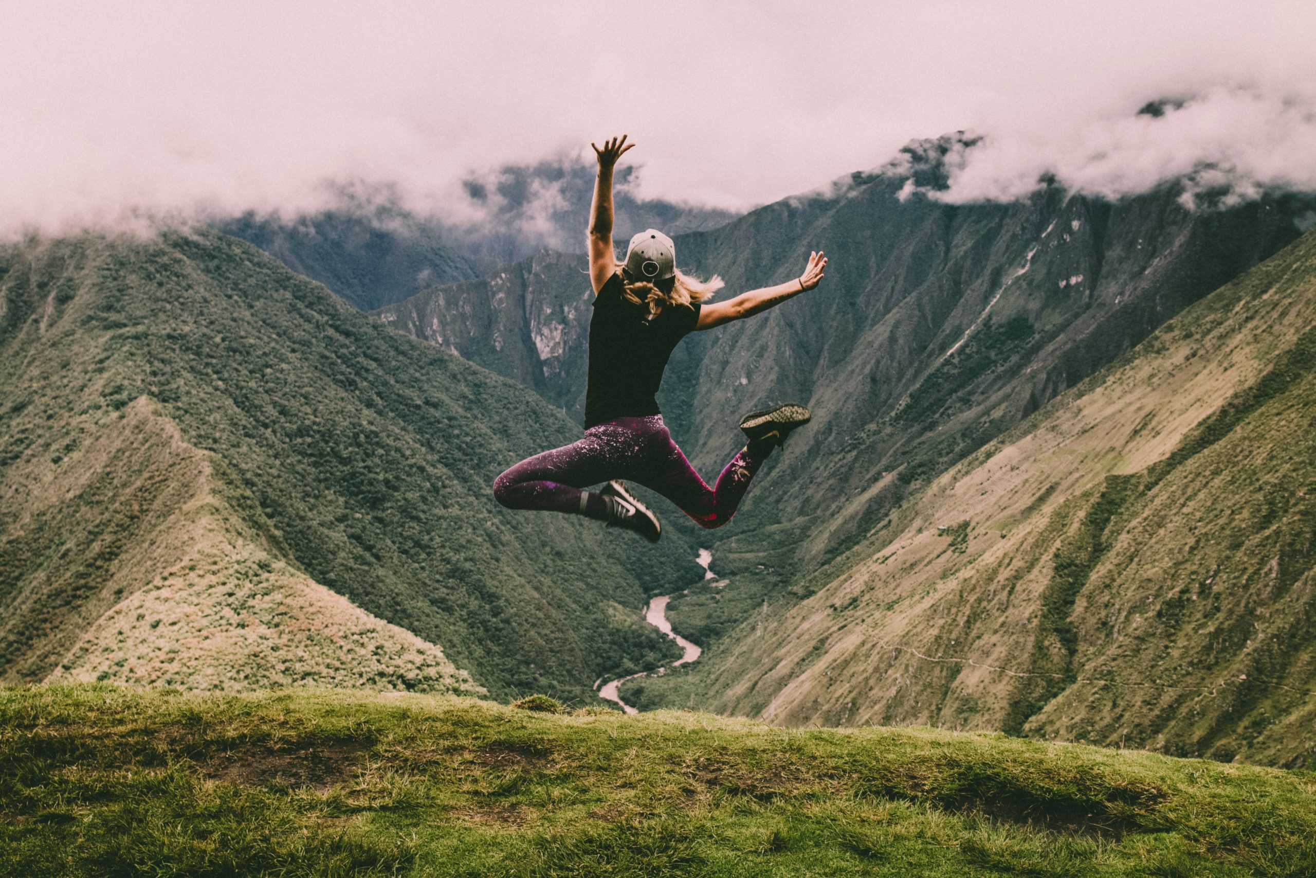 Woman jumping at top of mountain range
