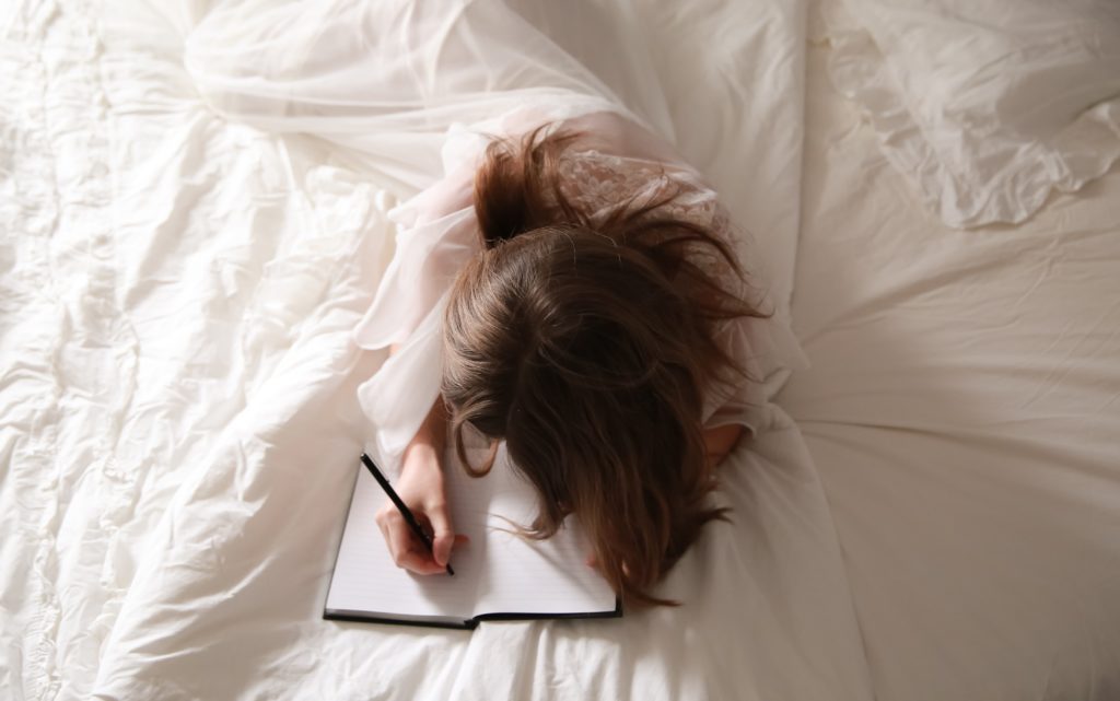 Woman writing in her bed.
