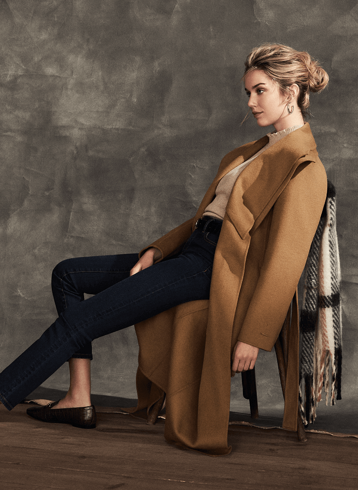 Model is lounging in a long belted coat by Tahari.